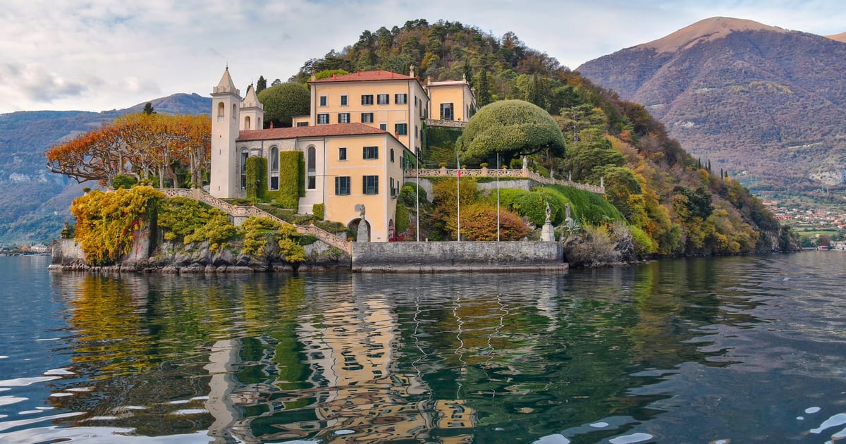 Η Villa del Balbianello στο δασωμένο ακρωτήρι της πάνω από τη λίμνη Κόμο, όπως φαίνεται από το νερό
